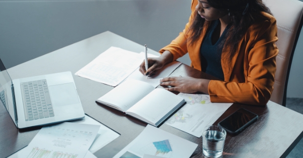 Woman writing on papers at desk