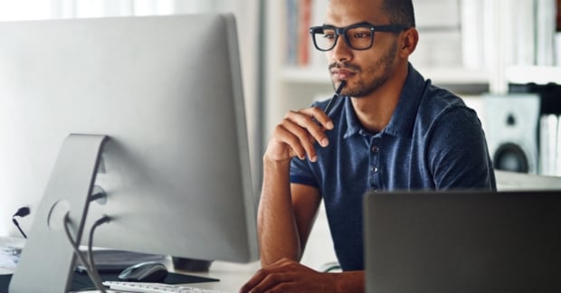 Man pondering in front of desktop computer