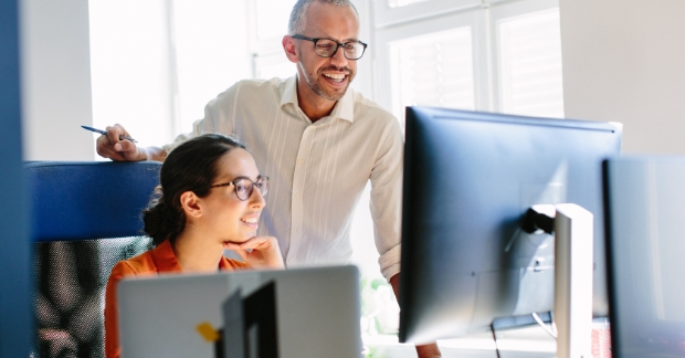 Coworkers reviewing work on desktop computer