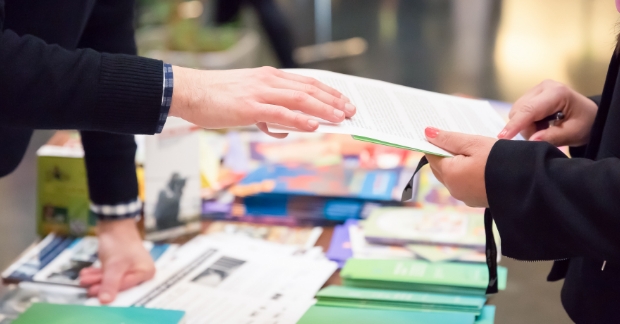 People exchanging marketing materials at trade show booth