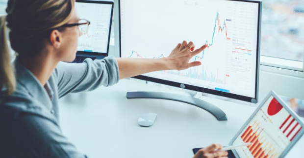 Woman pointing at computer screen with analytics displaying