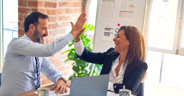 Man and woman hi-five over a laptop