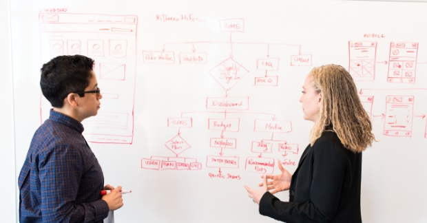 People talking strategy near a whiteboard