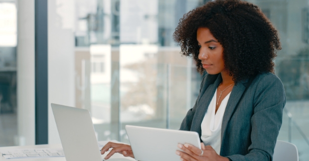 Woman in office looking at a computer and tablet screen