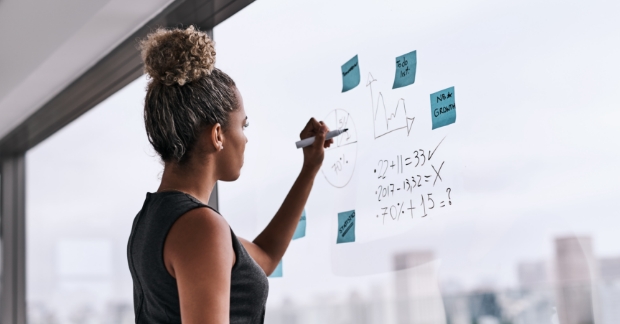 person writing down measuring tactics on Post-Its